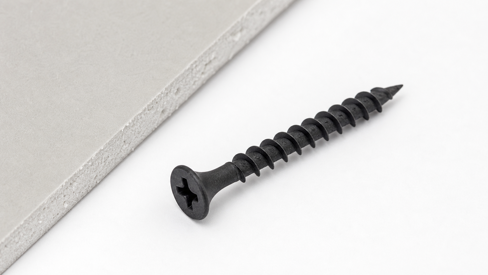 Close-up macro view of a black phosphate drywall screw showing the matte dark finish, bugle head, Phillips drive, coarse thre
