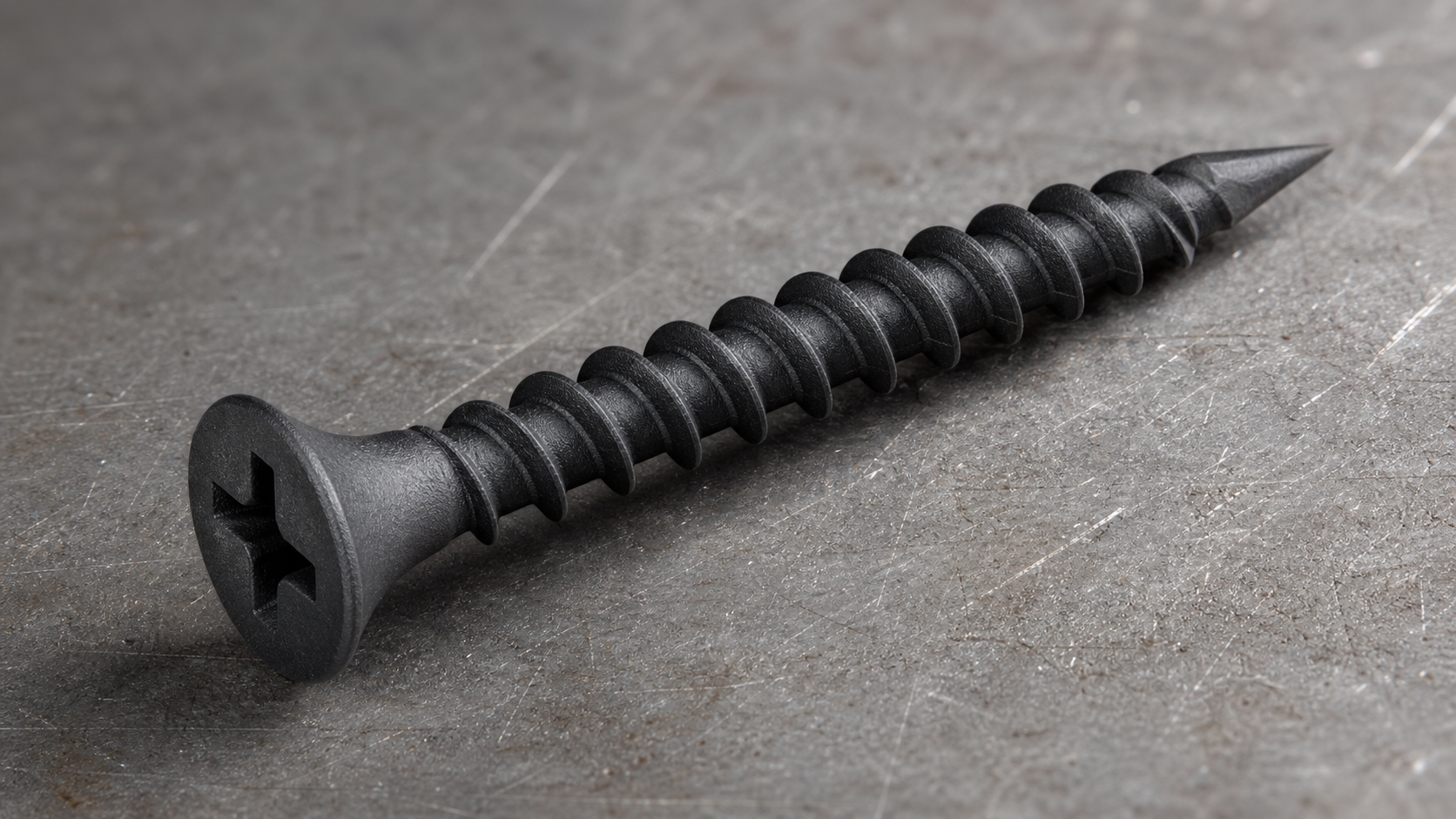 Close-up macro photograph of a single black phosphate drywall screw with a bugle head, Phillips drive, and a sharp needle-poi